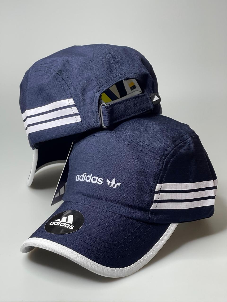 Boné Adidas azul marinho com logo branco, três listras e aba curva, em fundo neutro.