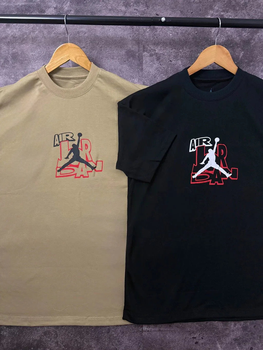 Camisetas Nike Air Jordan bege e preta com logo Jumpman ao centro, em cabides