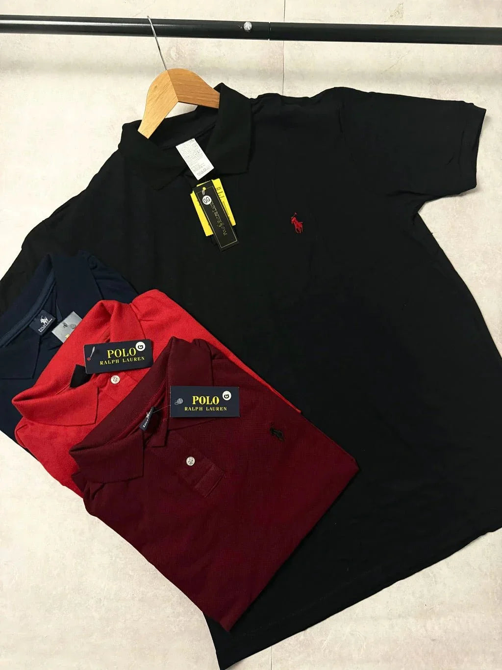 Camisas polo Ralph Lauren nas cores preta, vermelha, vinho e azul sobre superfície clara.