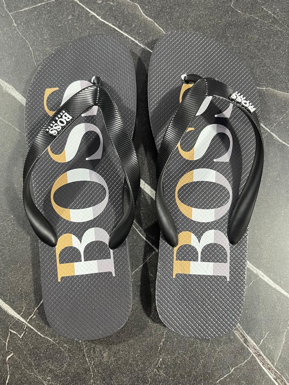 Chinelo preto Hugo Boss com logo grande, tiras pretas, sobre piso de mármore escuro