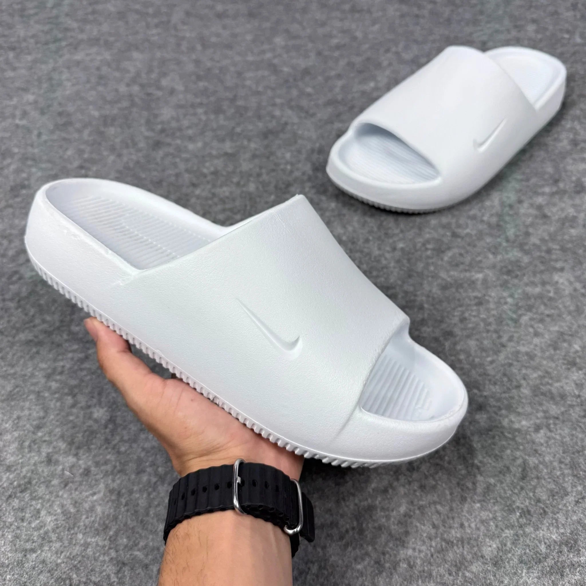 Chinelo Nike Calm Slide branco, emborrachado, sobre fundo cinza