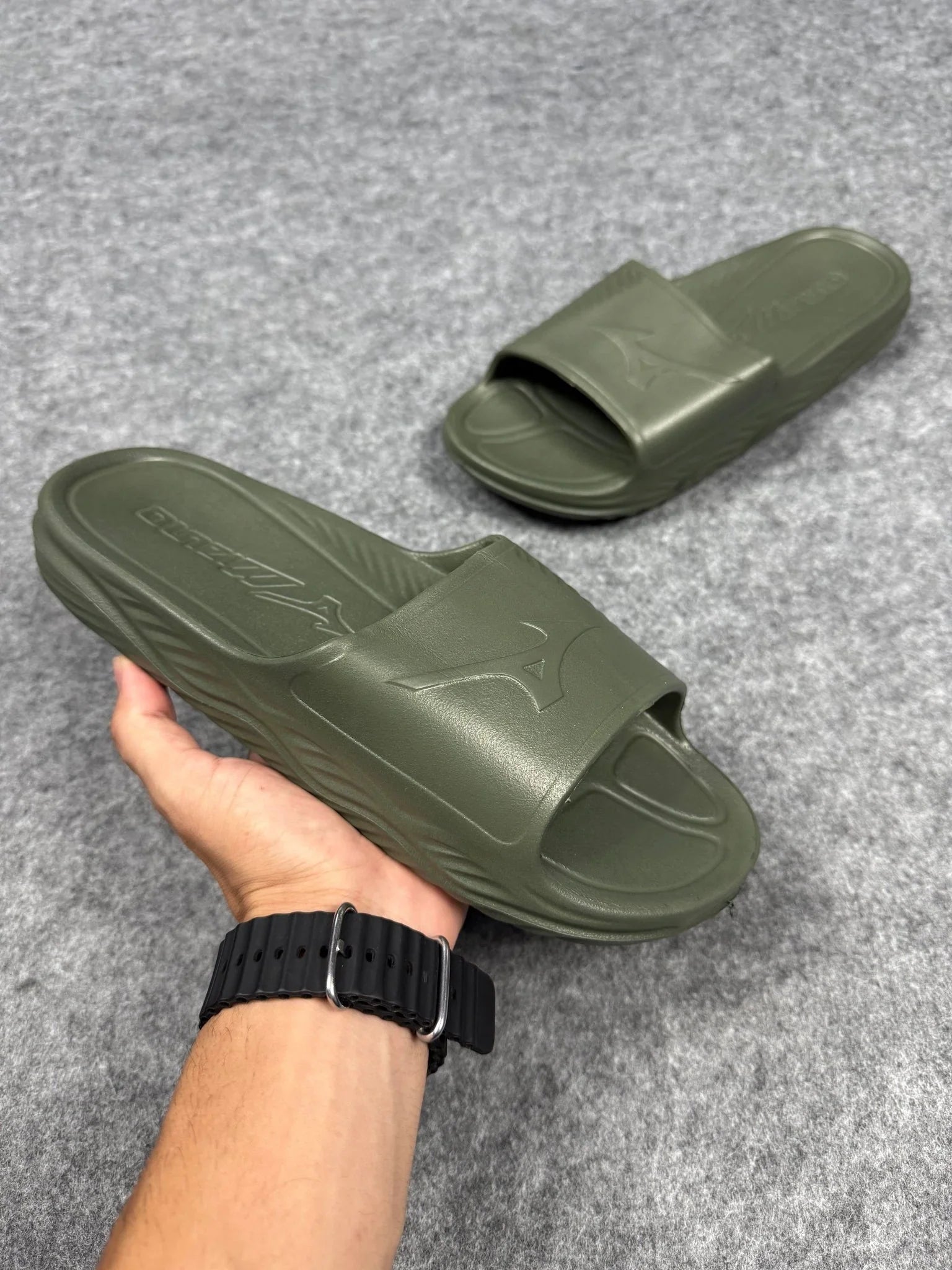 Chinelo slide Mizuno verde em material emborrachado sobre fundo cinza