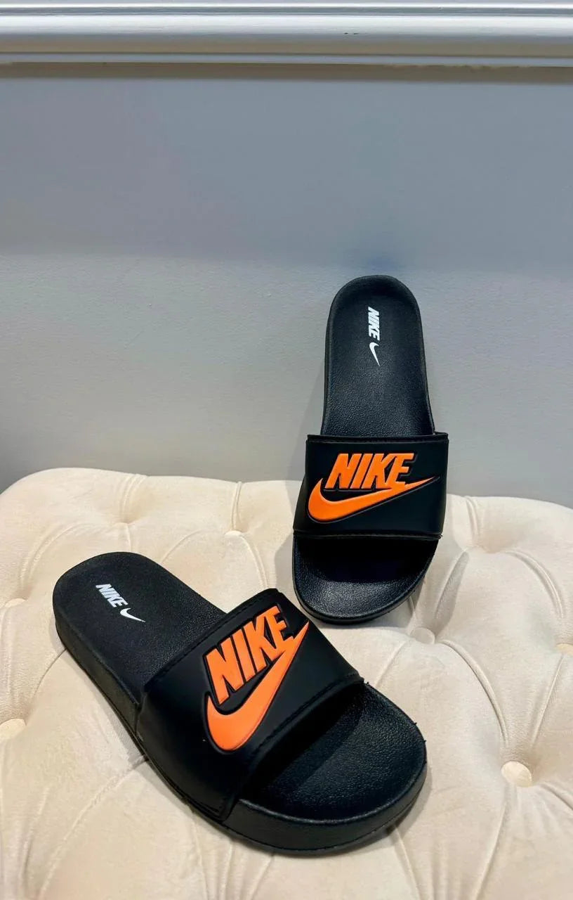 Chinelos slides Nike pretos com logo laranja sobre assento bege, moda casual