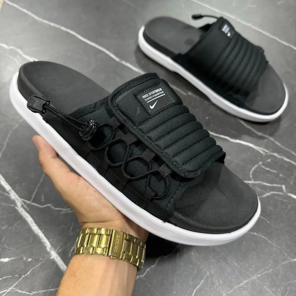 Chinelo Nike Asuna 2 preto com solado branco em mão, exibido em fundo de mármore.